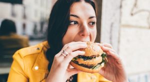 comportamento alimentar: moça comendo um hambúrguer